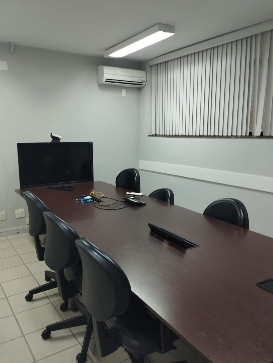 Sala de reunião do escritório da Via Sicura Assessoria, com mesa de reunião, cadeiras e televisão